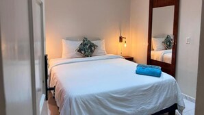 A bedroom with a bed, a nightstand, a mirror, and a wall-mounted light. - Boca Simon Vacation Curacao (Willemstad)