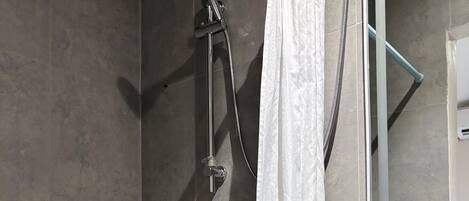 A shower with a handheld showerhead, a rain shower attachment, and a white shower curtain.
