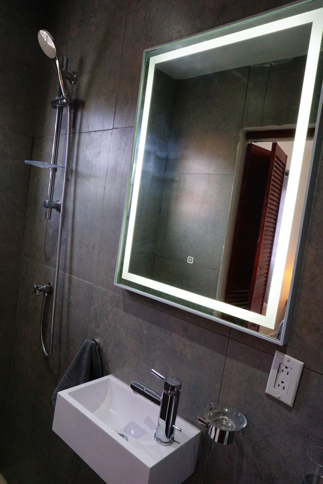 A modern bathroom with a large mirror, a shower, and a sink.