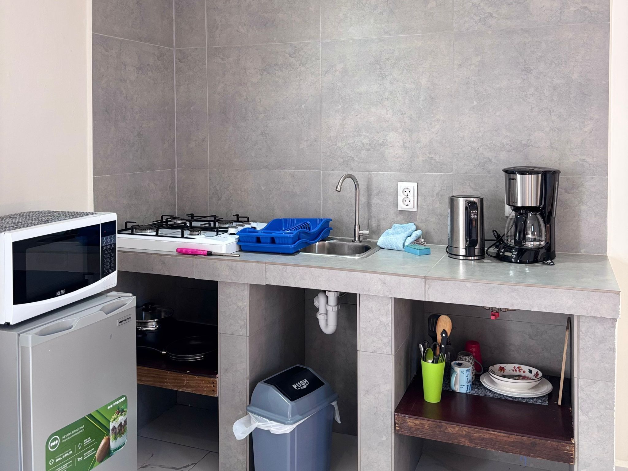 Una cocina compacta equipada con microondas, estufa, fregadero y cafetera.