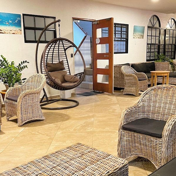 A room with wicker furniture, including chairs and a hanging chair, a wooden door, and a view of the outside. - Boca Simon Vacation Curacao (Willemstad)