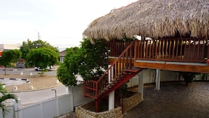 A building with a thatched roof and a wooden staircase leading to a balcony. - Boca Simon Vacation Curacao (Willemstad)