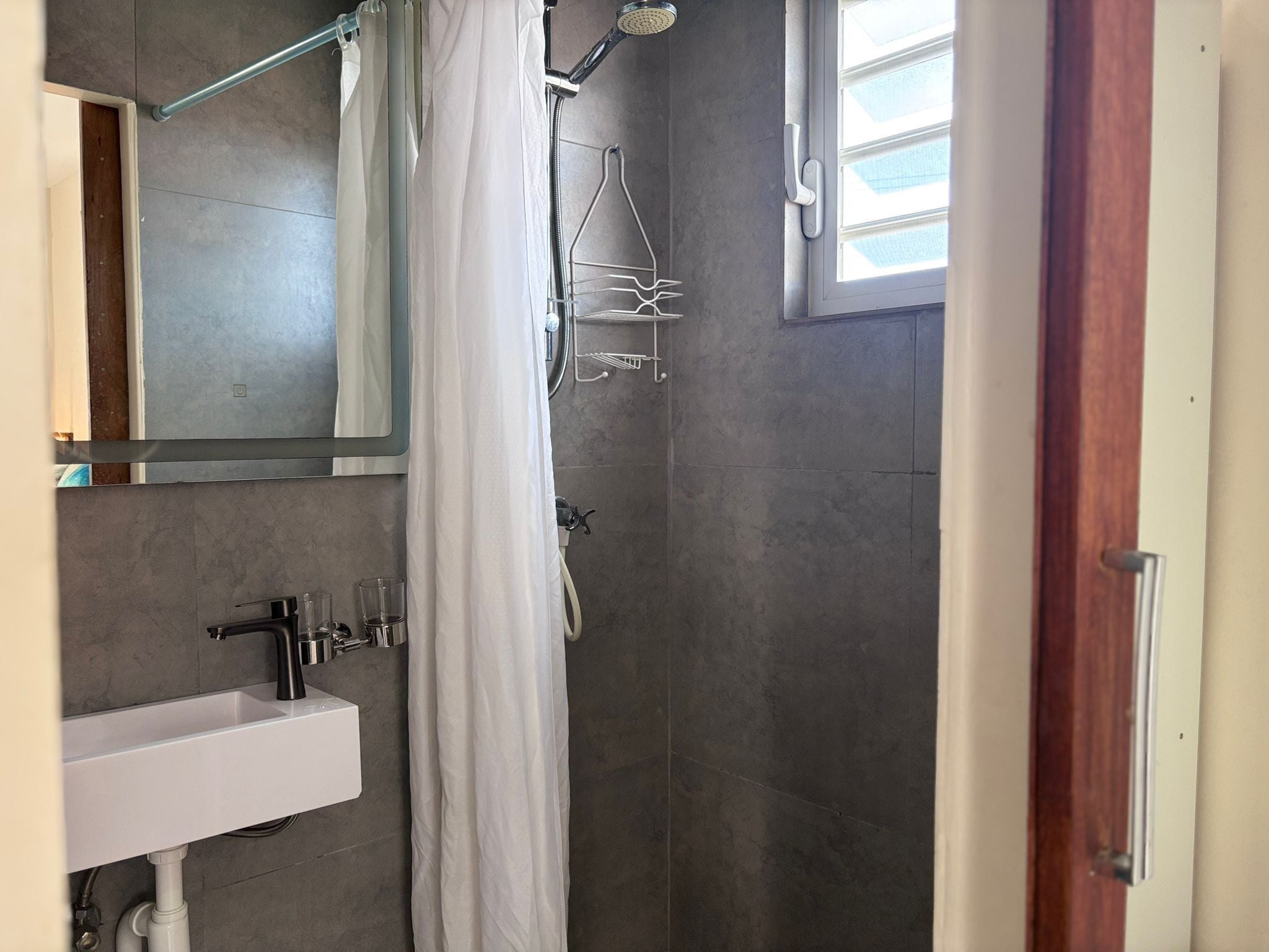 A modern bathroom with a shower, a sink, and a mirror.
