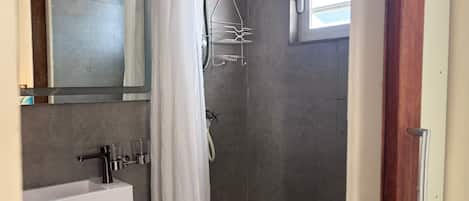 A modern bathroom with a shower, a sink, and a mirror.