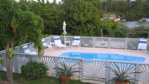 A pool area with white lounge chairs and a blue pool.