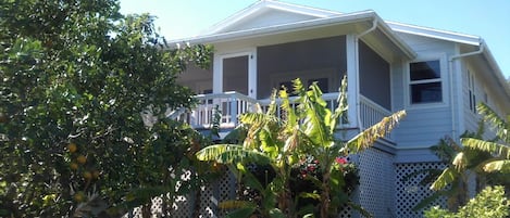 A two-story house with a covered porch and a white fence.