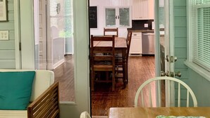 Una habitación acogedora con una mesa de comedor de madera, un sofá y una puerta que da a una zona de cocina.