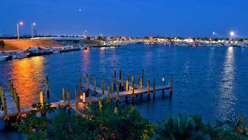 A marina with docked boats, a wooden pier, and a cityscape in the background.
