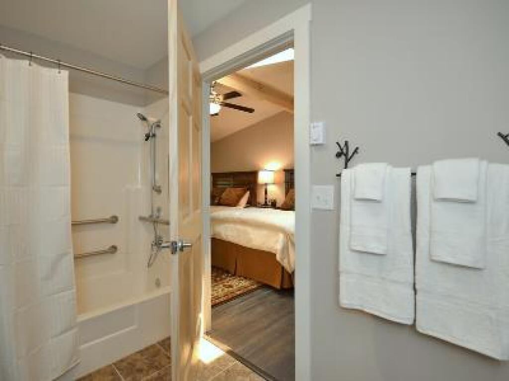 A hotel room with a shower, a bed, and a wall-mounted towel rack.