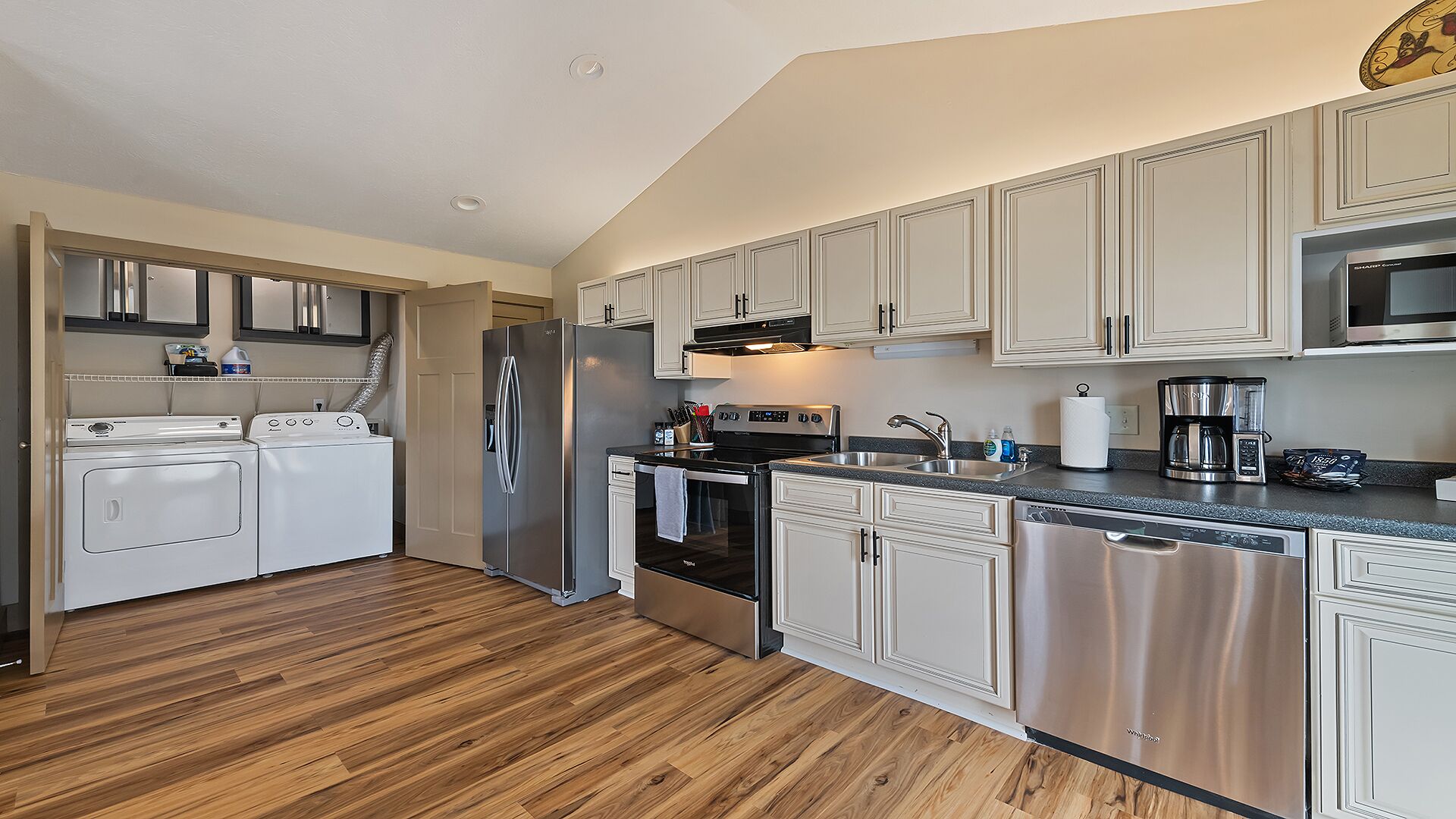 A compact kitchen with a washer-dryer unit, stainless steel appliances, and white cabinetry.