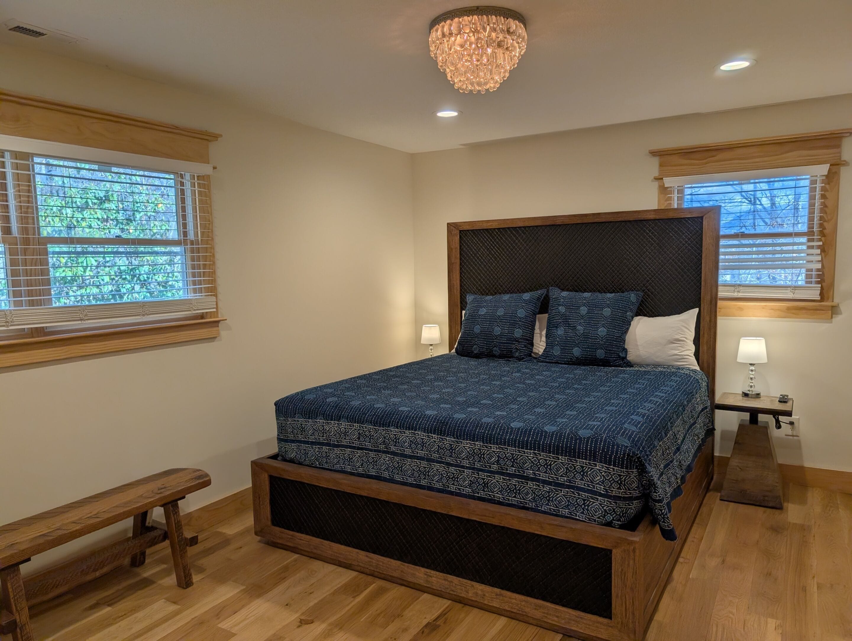 A bedroom with a large bed, wooden headboard, and a bench.