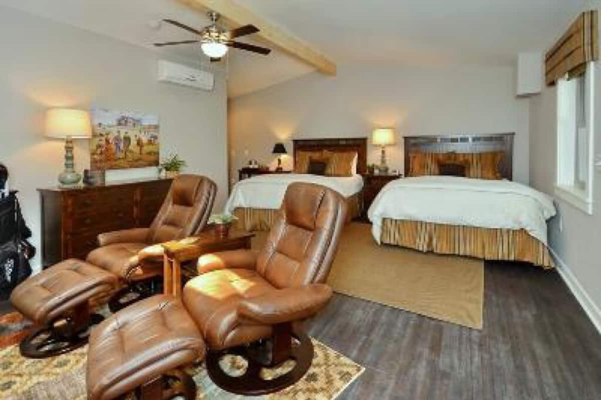 Habitación de hotel con un sofá, dos camas, un ventilador de techo y un ventanal grande.