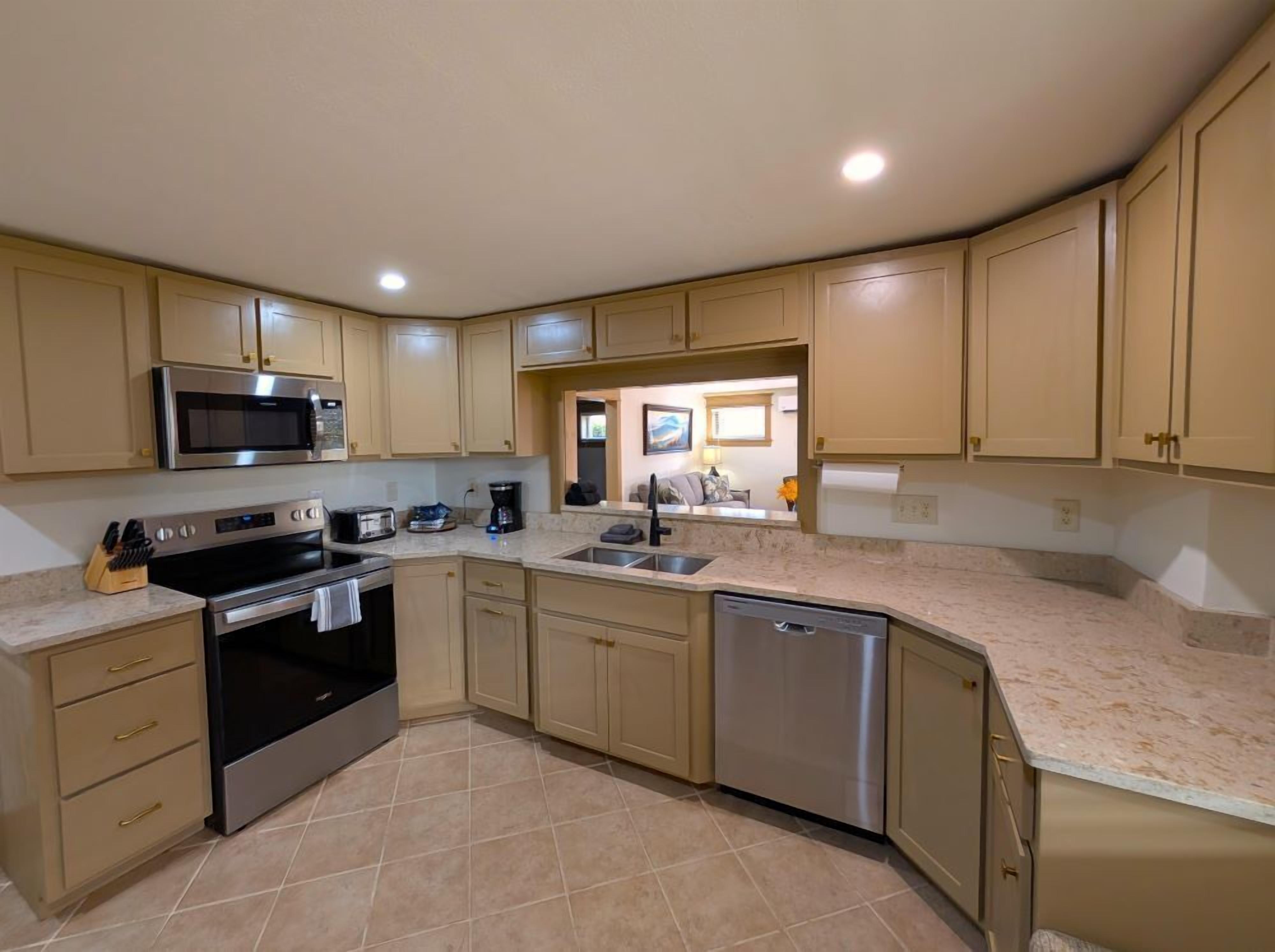 A modern kitchen with beige cabinets, stainless steel appliances, and a dishwasher.