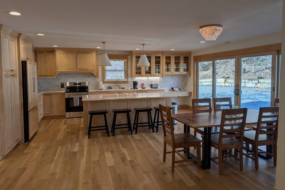 Una cocina moderna con armarios de madera, una isla grande y un comedor con sillas.