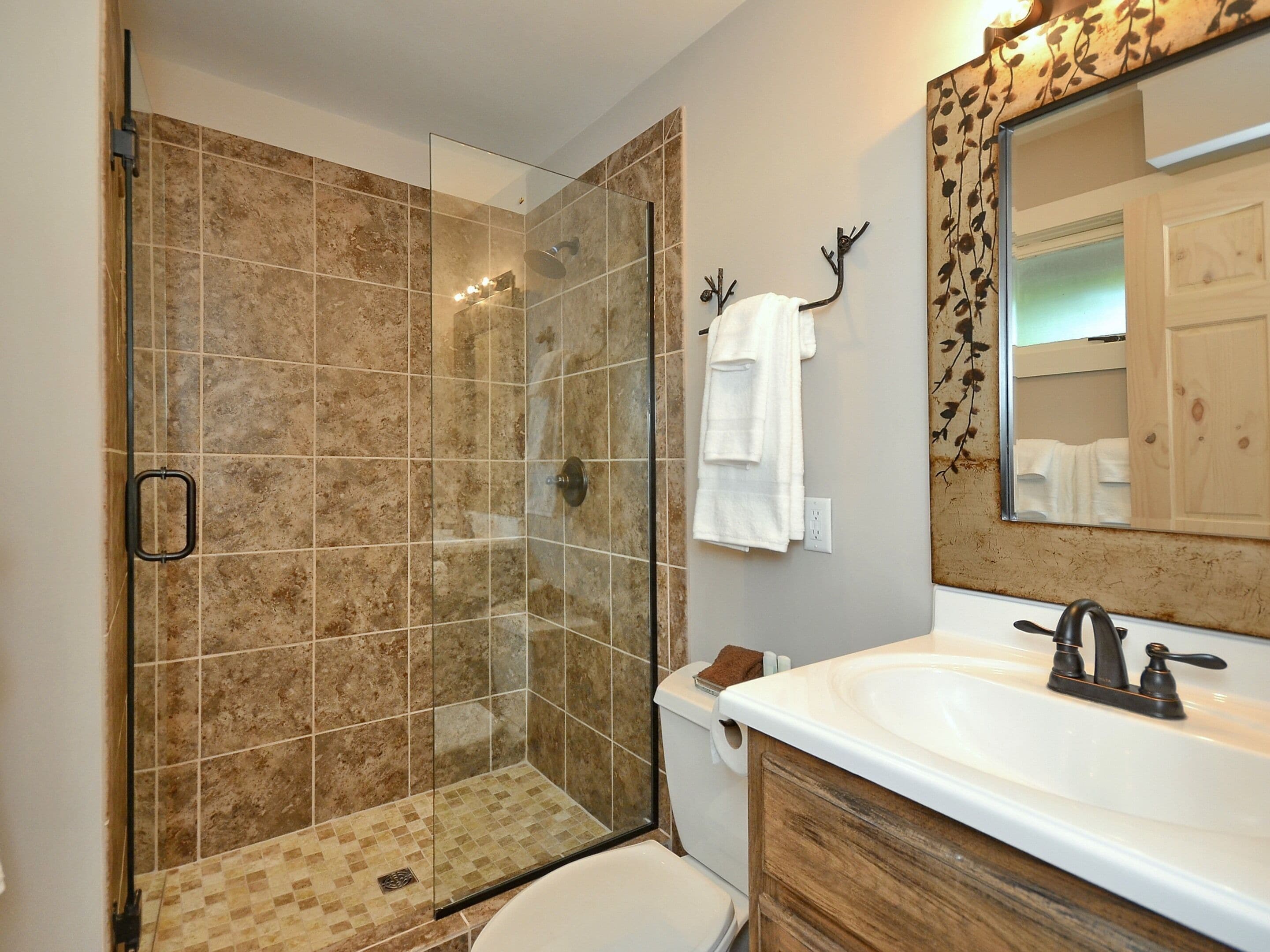 A bathroom with a glass-enclosed shower, a white sink, and a wooden vanity.