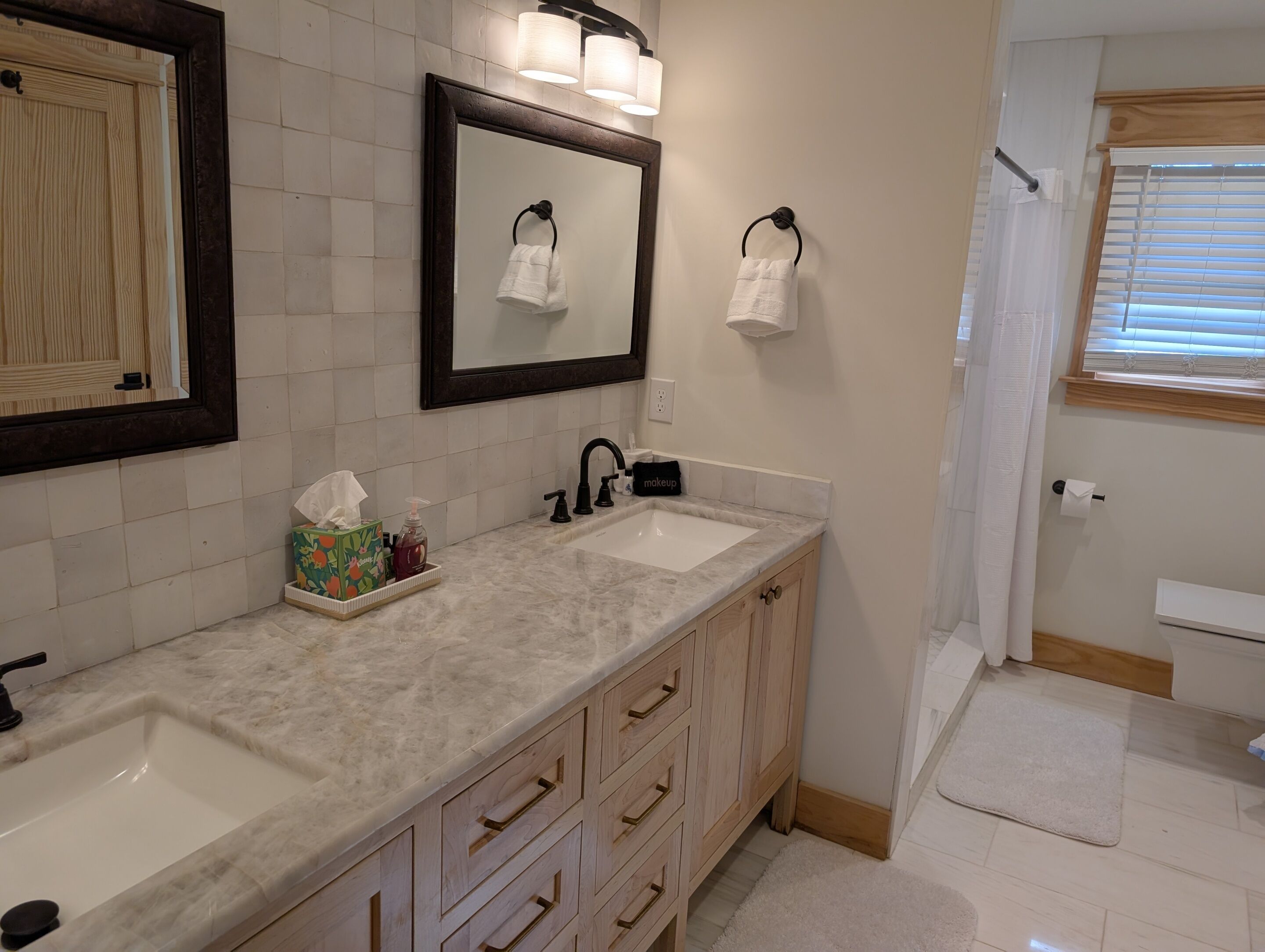 Un baño con dos lavamanos, un espejo y un mueble de tocador con cajones.