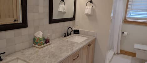 Un baño con dos lavamanos, un espejo y un mueble de tocador con cajones.