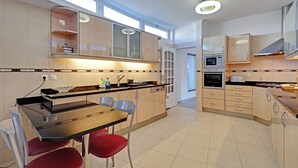 Een moderne keuken met een eethoek, met een glazen tafel, rode stoelen en inbouwapparatuur.