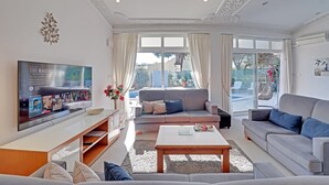 Een moderne woonkamer met een flatscreen televisie, grijze banken, een salontafel en een balkon met uitzicht.