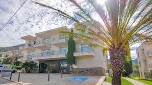A multi-story building with a wheelchair-accessible entrance, palm trees, and a paved area with a blue handicap parking symbol. - Rescator Resort 215 - One Bedroom Apartment, Sleeps 4 (Roses)