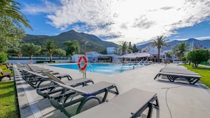 A poolside area with sun loungers and a lifebuoy, surrounded by greenery and mountains. - Rescator Resort 215 - One Bedroom Apartment, Sleeps 4 (Roses)