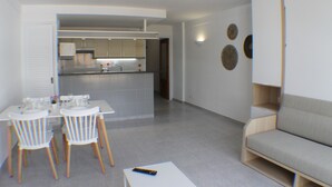 A modern living space with a dining area, kitchen, and seating area.