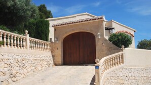 A stone pathway leading to a large wooden door with a stone wall on one side and a balustrade on the other. - Villa Luna del mar Su (Benissa)