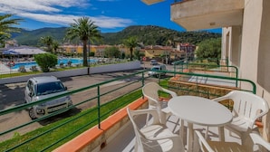 A balcony with a view of a swimming pool, palm trees, and a mountainous landscape. - Rescator Resort 229 - One Bedroom Apartment, Sleeps 4 (Roses)