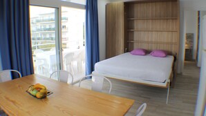 A bedroom with a bed, a wooden table with fruit, and a balcony with chairs. - Rescator Resort 302 - Two Bedroom Apartment, Sleeps 6 (Roses)