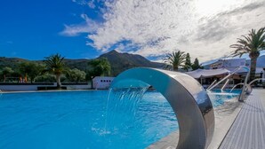 Ein Pool mit einer geschwungenen Wasserspielfeature, umgeben von Palmen und Gebäuden.