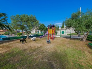 A playground with a slide and climbing structures, surrounded by trees and a fenced area. - Rescator Resort 118 - One Bedroom Apartment, Sleeps 4 (Roses)