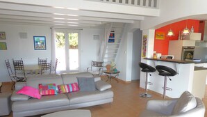 A modern living room with a sofa, two armchairs, a coffee table, and a kitchen area with a bar and seating. - Villa for 6 People with Pool and Unobstructed View (LA LONDE LES MAURES)