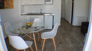 A modern kitchen with white cabinets, a built-in microwave, and a glass dining table with four white chairs. - Rescator Resort 225 - One Bedroom Apartment, Sleeps 4 (Roses)