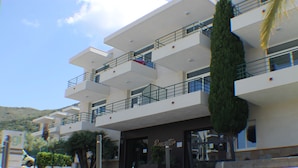 A multi-story building with balconies, a sign reading "Resort", and a palm tree in front. - Rescator Resort 225 - One Bedroom Apartment, Sleeps 4 (Roses)