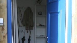 A blue door leading to a room with a white shelf, a clock, and two umbrellas. - Pretty Cozy 3 * house, green 7/8 pers St Gildas de Rhuys, 1km bg, 2km beach (Saint-Gildas-De-Rhuys)