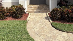 A two-story house with a front entrance, a covered patio, and a landscaped garden.