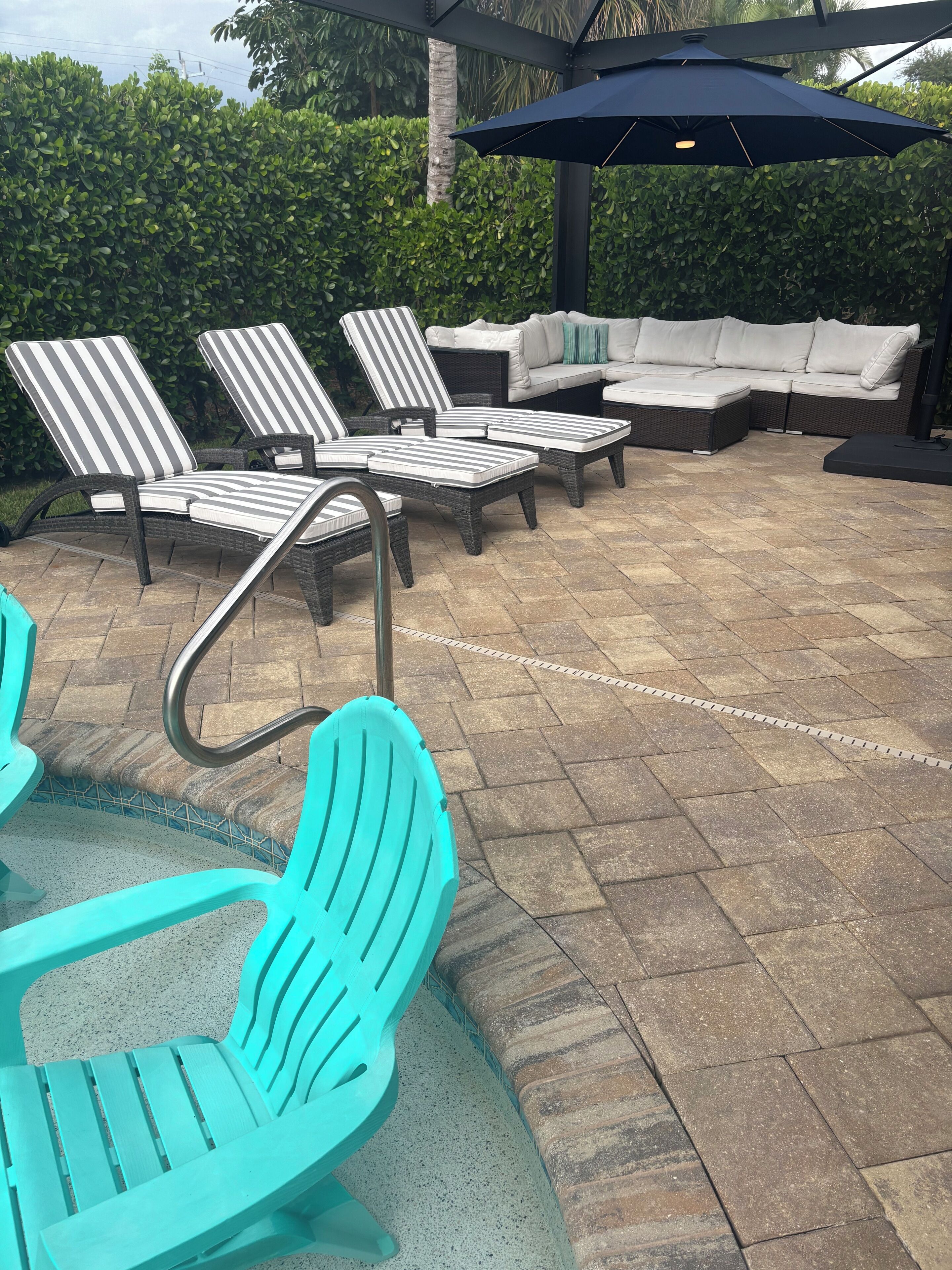 A patio area with outdoor furniture including striped lounge chairs, a sofa, and a pool table.