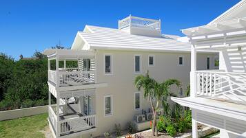A two-story building with a balcony on the upper floor and a covered outdoor area with a pool table.