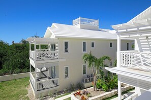 A two-story building with a balcony on the upper floor and a covered outdoor area with a pool table. - Anchor Point Apartments (Governor's Harbour)