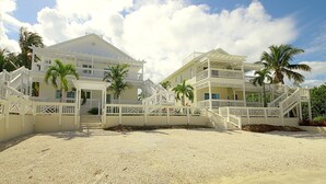 A beachfront property with two-story buildings, multiple balconies, and a sandy beach in front. - Anchor Point Apartments (Governor's Harbour)
