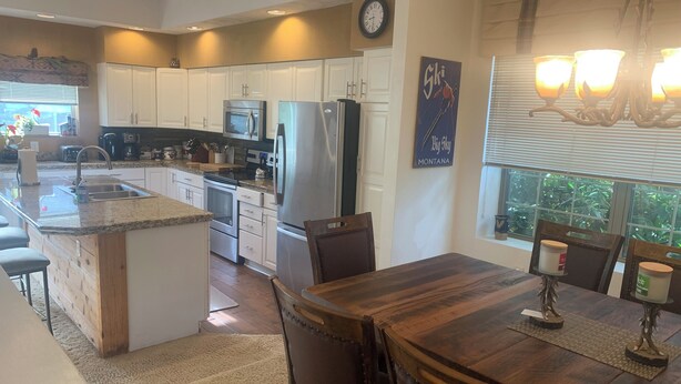A modern kitchen with white cabinets, stainless steel appliances, and a wooden dining table. - Experience All 7 Springs Has to Offer in This Great Townhouse (Champion)