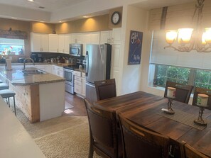 A modern kitchen with white cabinets, stainless steel appliances, and a wooden dining table. - Experience All 7 Springs Has to Offer in This Great Townhouse (Champion)