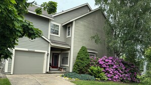 A two-story house with a garage, a front porch, and a well-maintained garden with flowering bushes. - Experience All 7 Springs Has to Offer in This Great Townhouse (Champion)