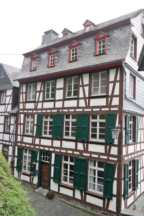 A traditional half-timbered building with multiple windows and a door, featuring a mix of white and brown timber framing. - Haus Stehlings (Monschau)