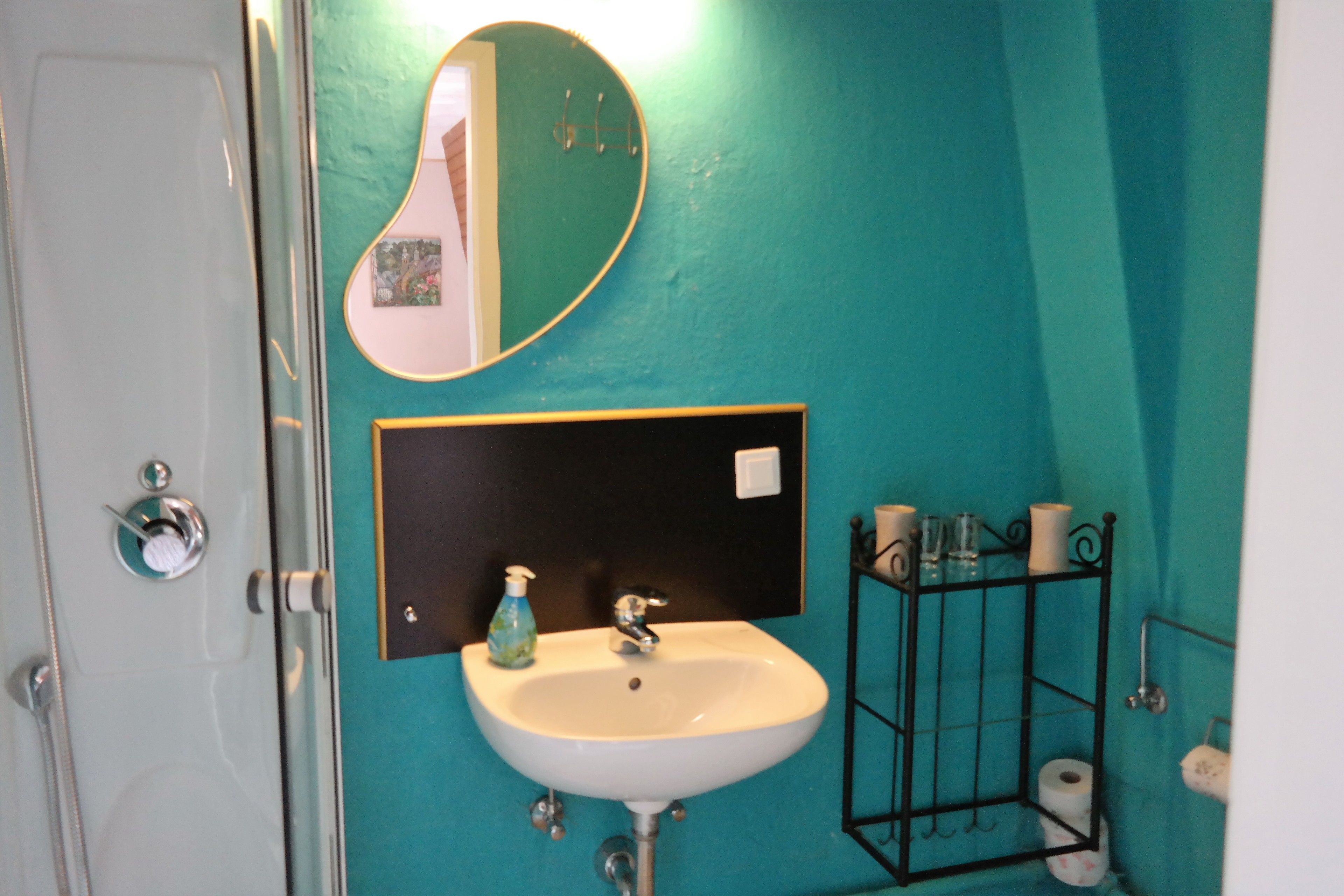 Un baño con un lavamanos blanco, un espejo y un perchero para toallas.