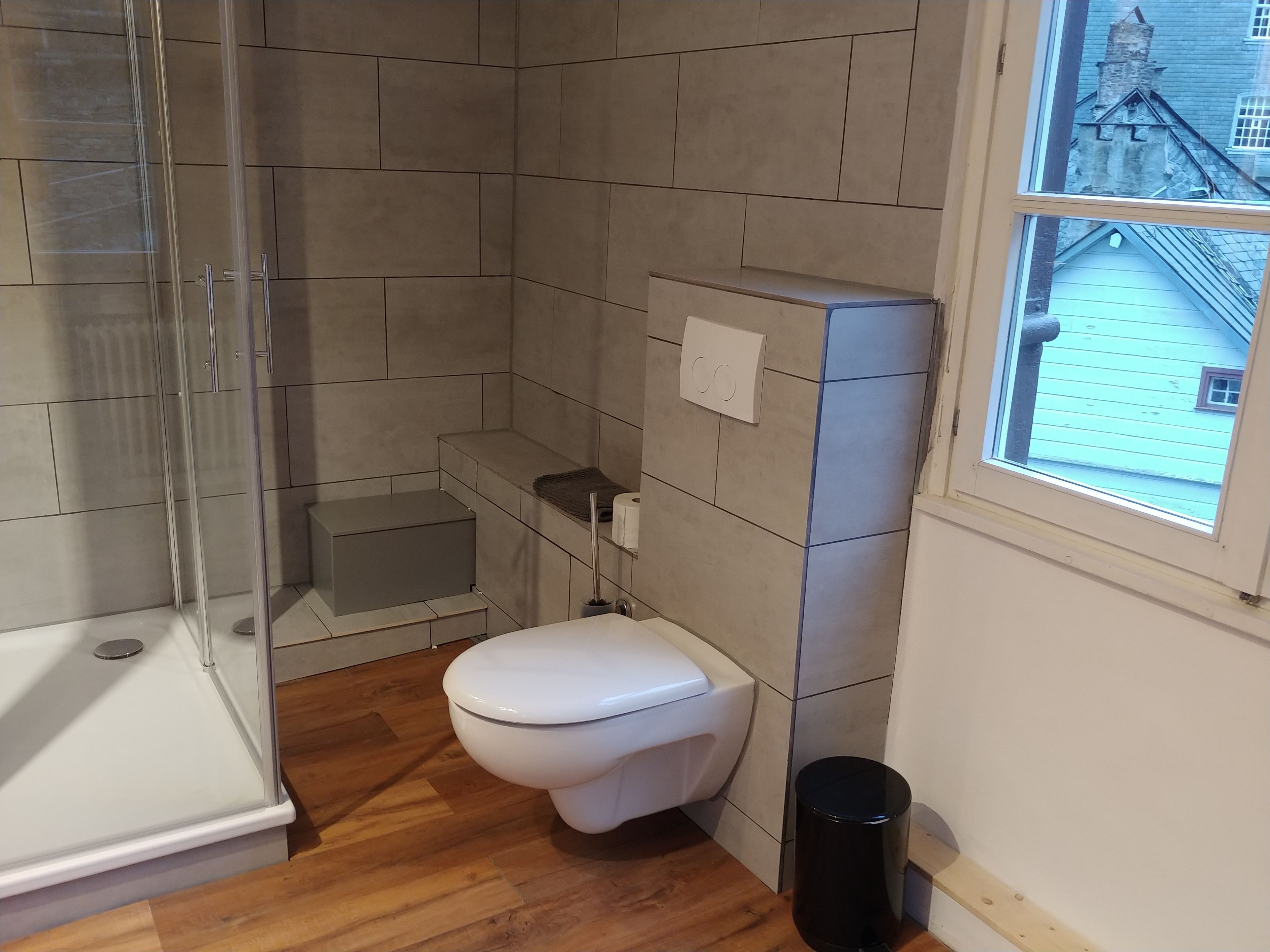 A bathroom with a shower, toilet, and a window.