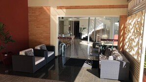 A lobby with a glass door entrance, a reception desk, and seating areas. - Hotel Giordano Mantiqueira (Sao Joao da Boa Vista)
