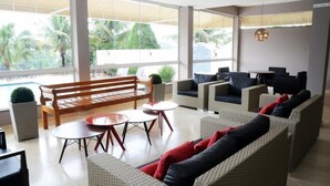 A modern lounge area with wicker furniture, a wooden bench, and a pool view. - Hotel Giordano Mantiqueira (Sao Joao da Boa Vista)