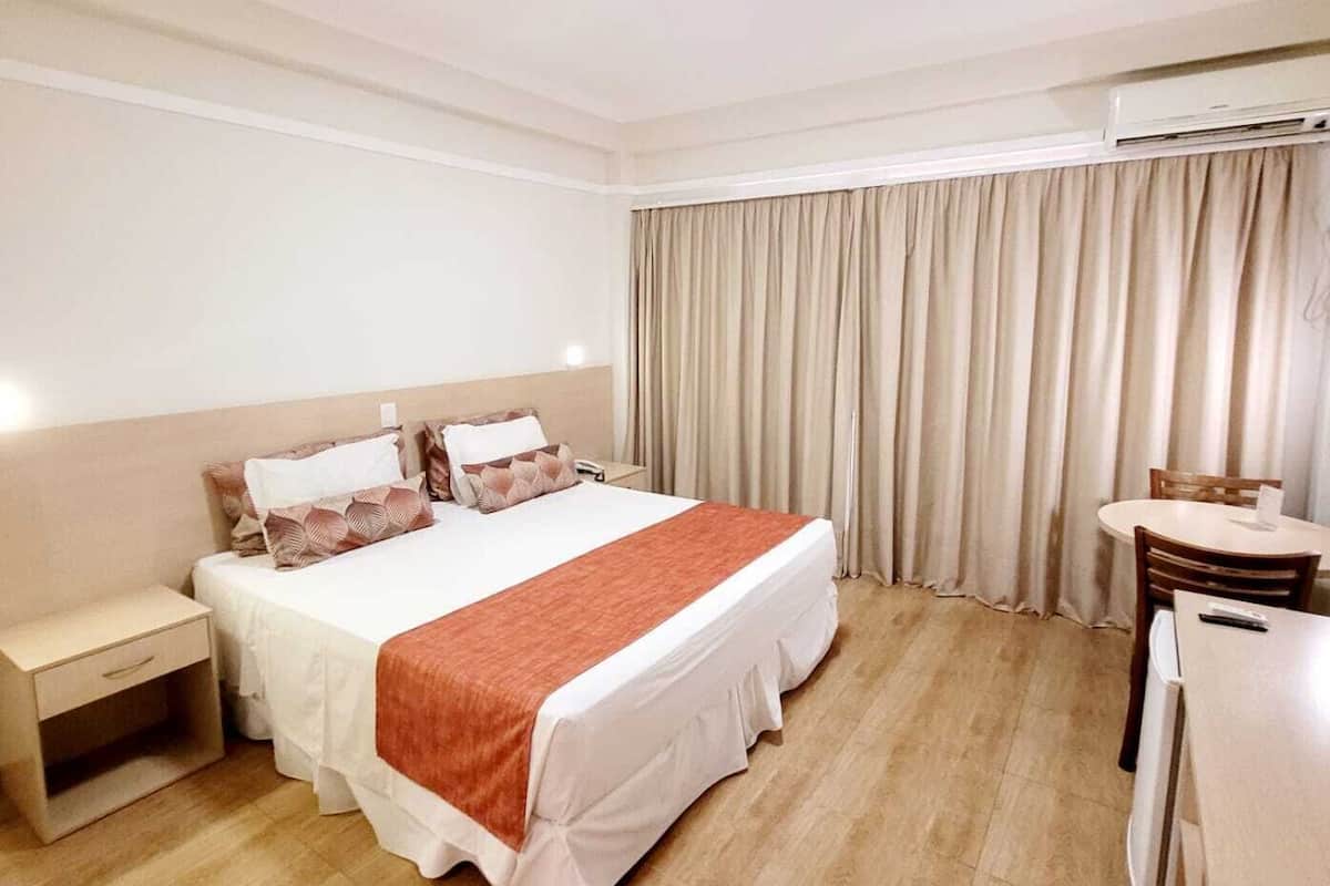 Une chambre d’hôtel avec un grand lit, une table de chevet, un bureau et une chaise.