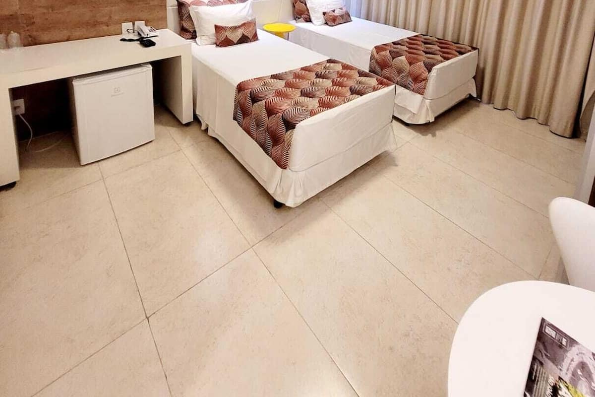Une chambre d’hôtel avec deux lits, un bureau, un mini-réfrigérateur et une chaise.